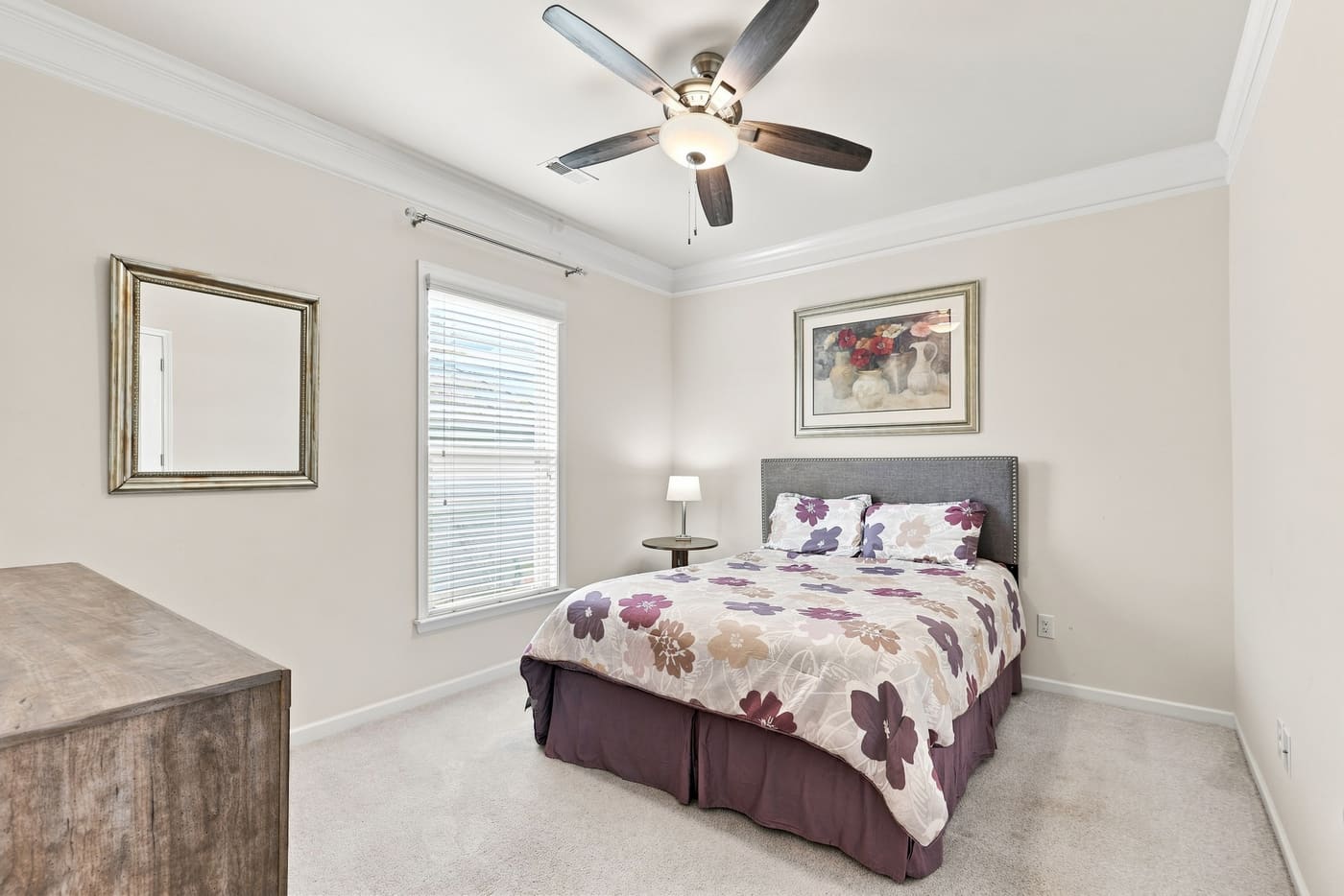 A secondary bedroom with carpet, a window and a ceiling fan.