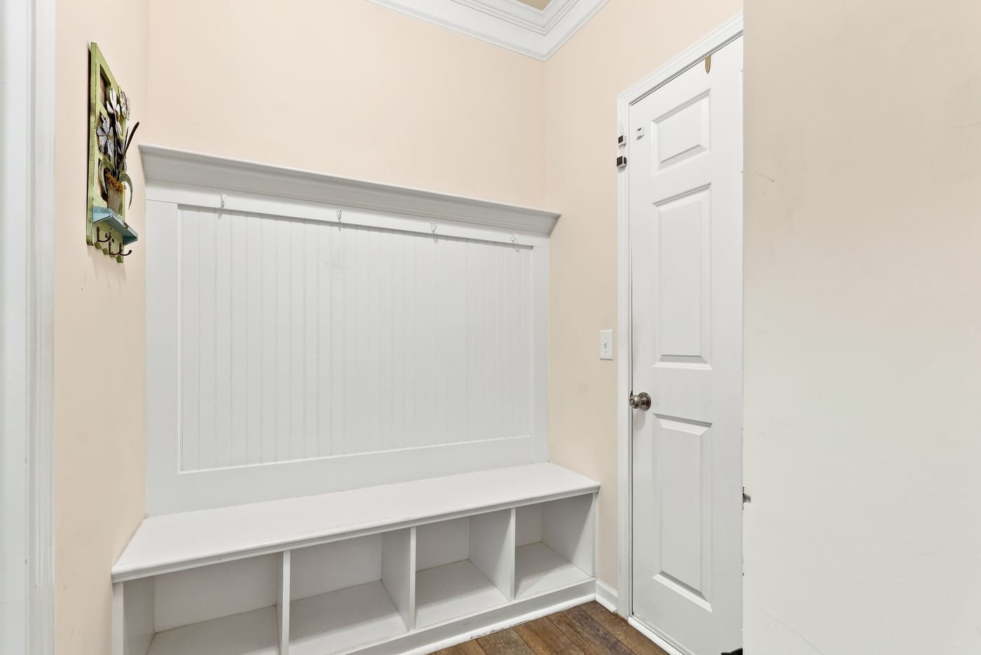 A built-in bench with hooks and cubbies beside the door from the garage.