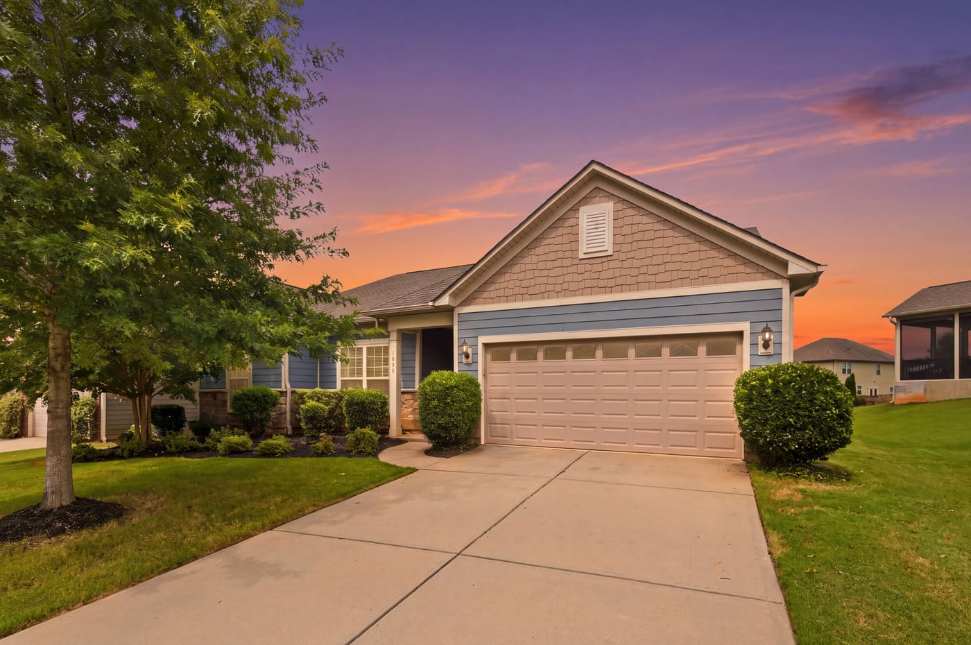 The front elevation of 1030 Squire Drive at dusk, with the sky turning amber above the roofline.