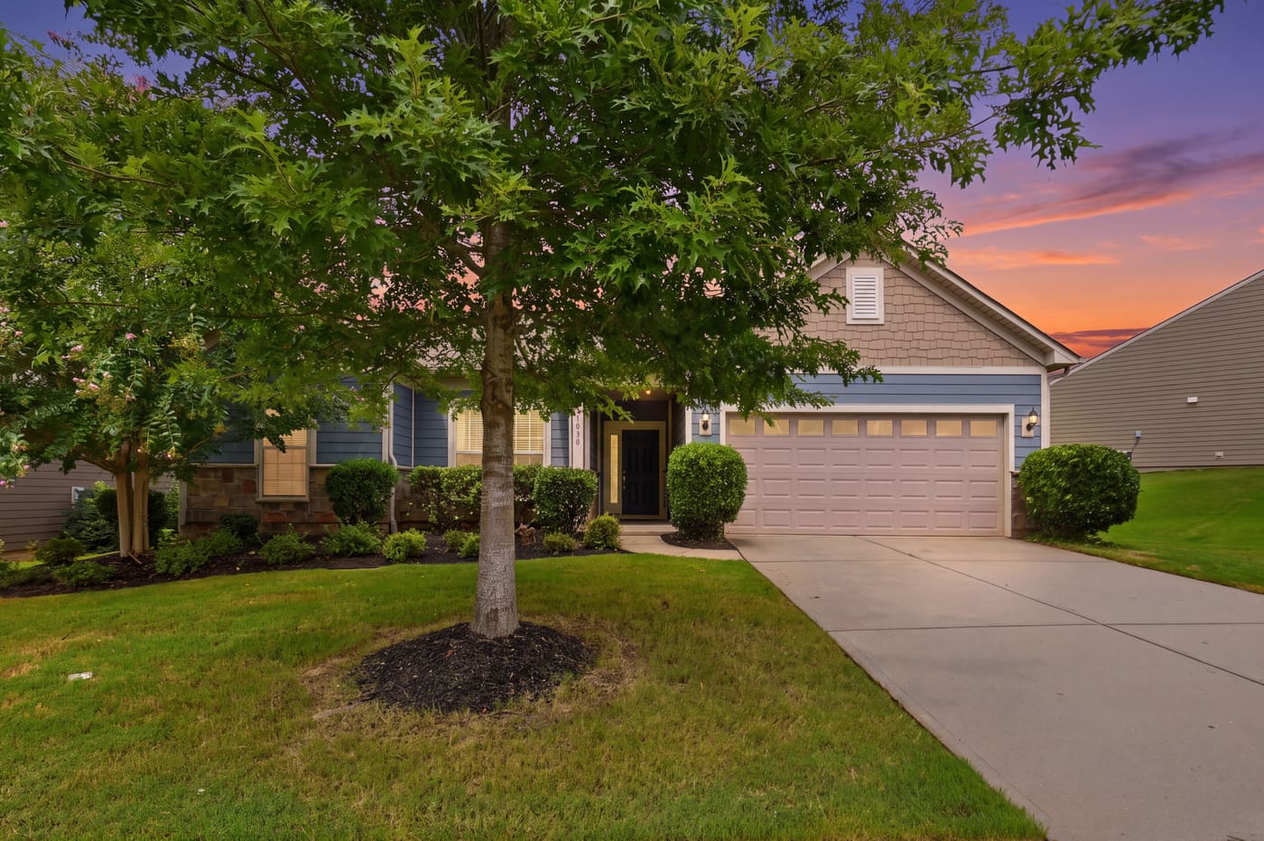 The house at dusk seen past the crepe myrtle in the front yard.