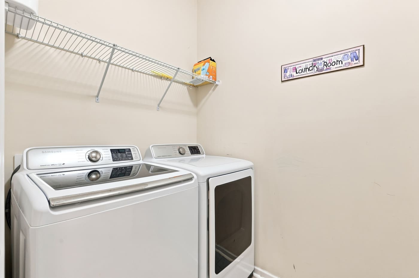 The main-level laundry room with a washer and dryer and wire shelving above.