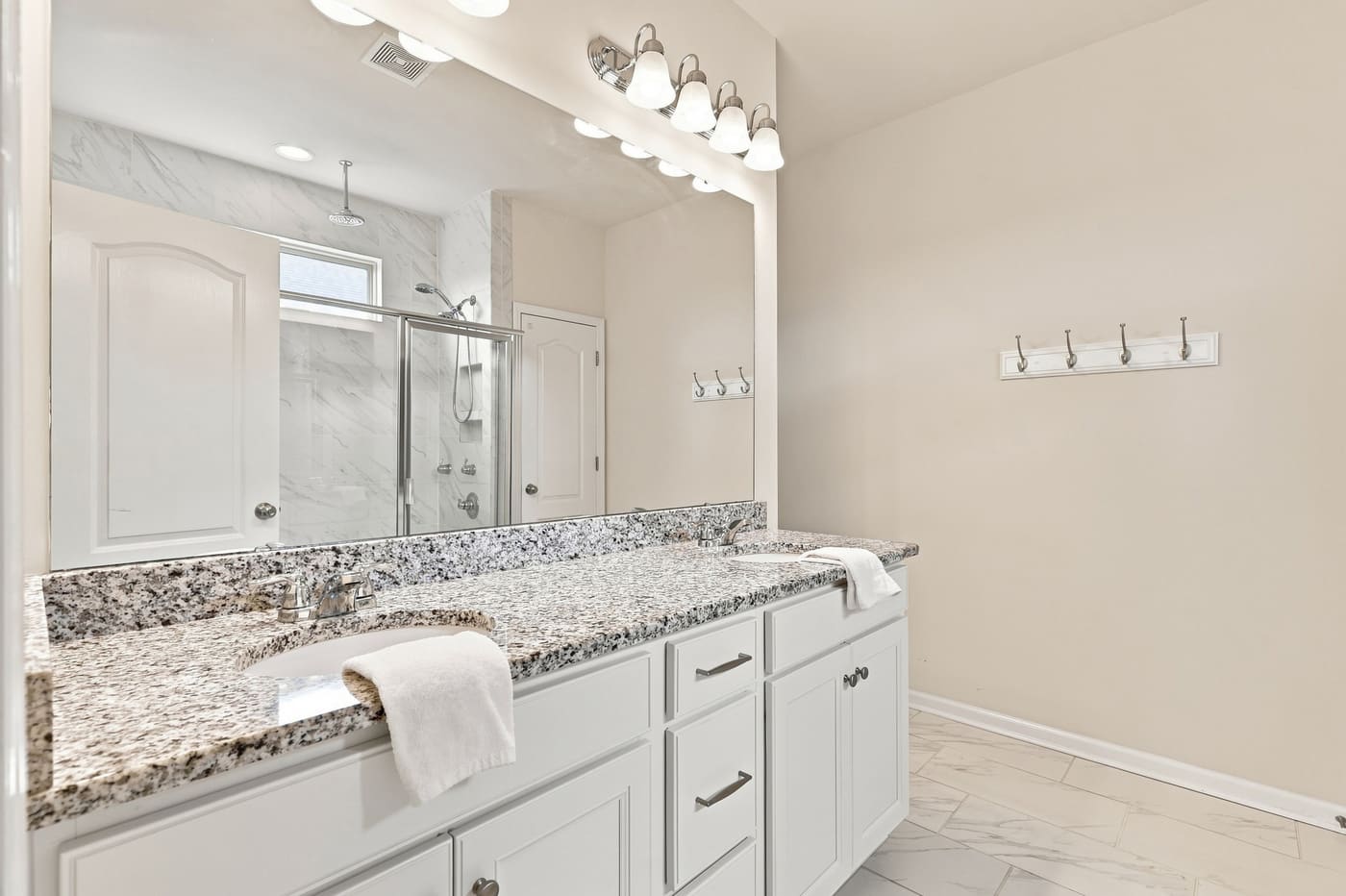 The primary bath with a granite vanity, wide mirror and a glass-enclosed shower.