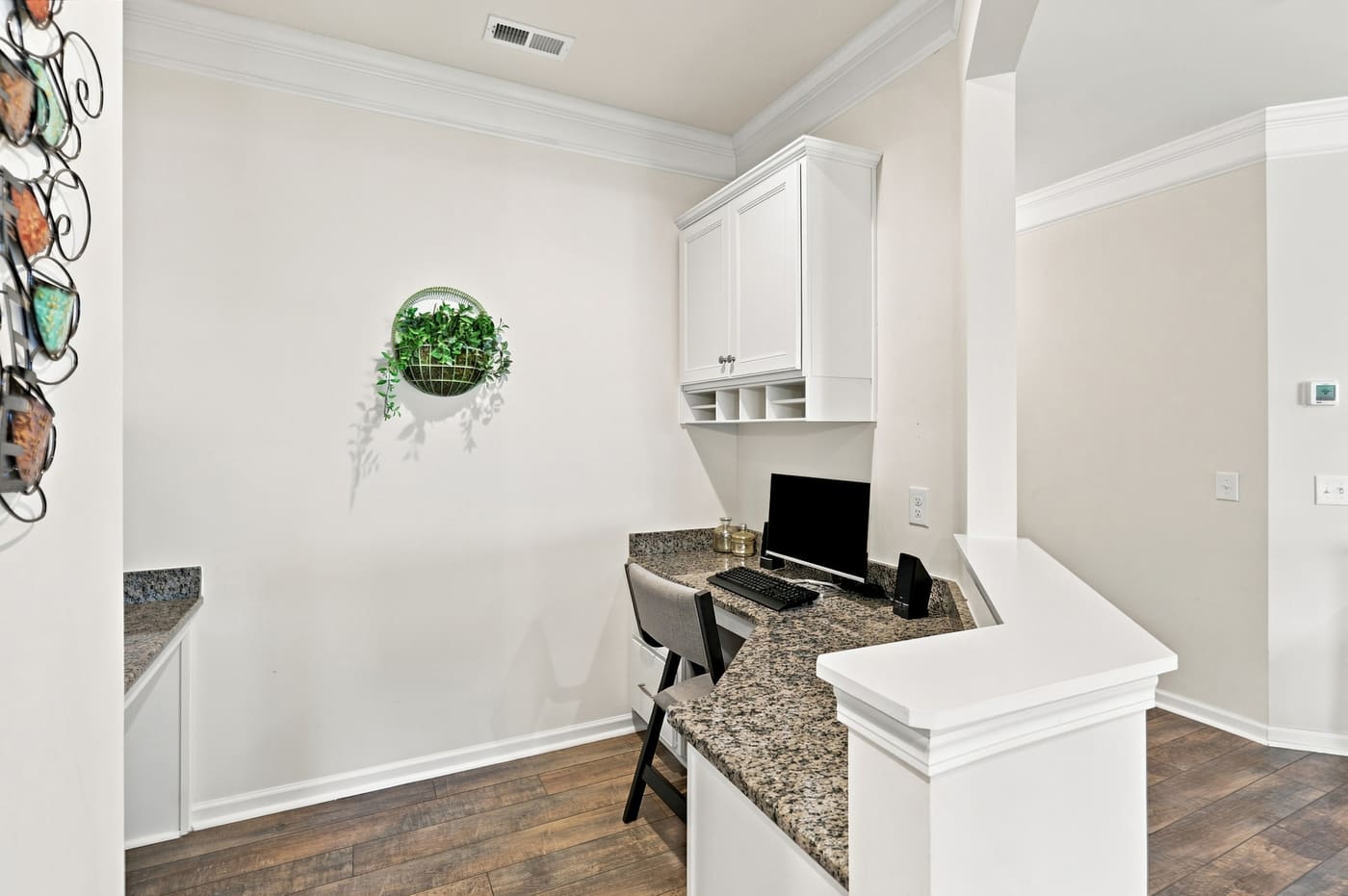 A built-in workstation with a granite top and upper cabinets, set into an alcove off the kitchen.